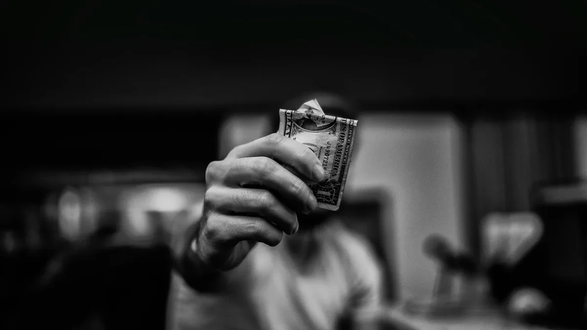 Gambling Addiction: Black and white photo of man holding a dollar bill Gambling Addiction: Black and white photo of man holding a dollar bill