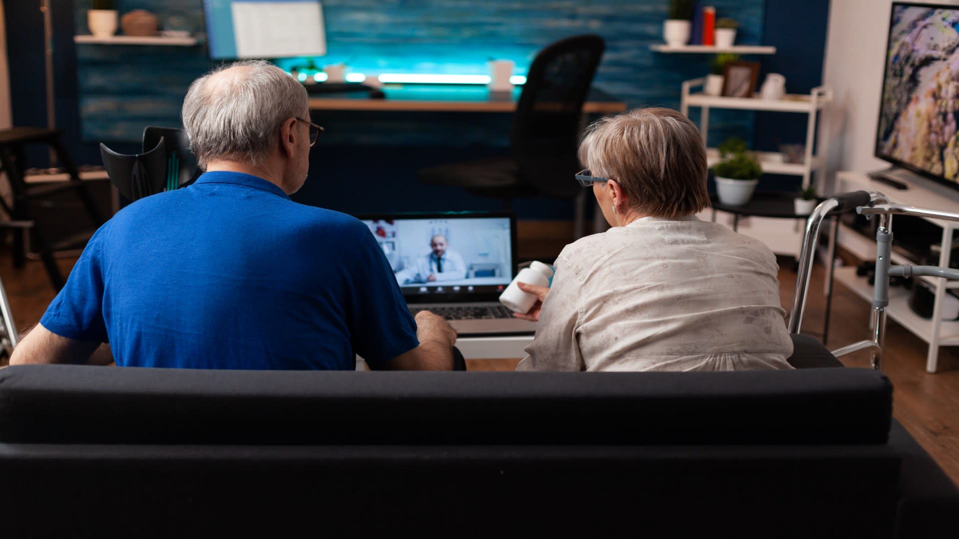Senior couple attending an online addiction counseling session with a doctor via laptop from their living room.