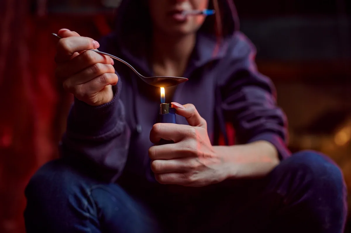 Meth Addiction: Woman holding a lighter under a spoon Meth Addiction: Woman holding a lighter under a spoon