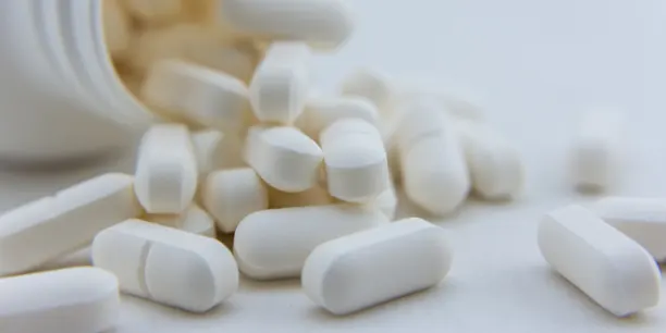 Picture of white pills and a pill bottle.