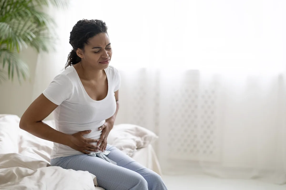 Food Addiction: Woman in pain sitting on her bed