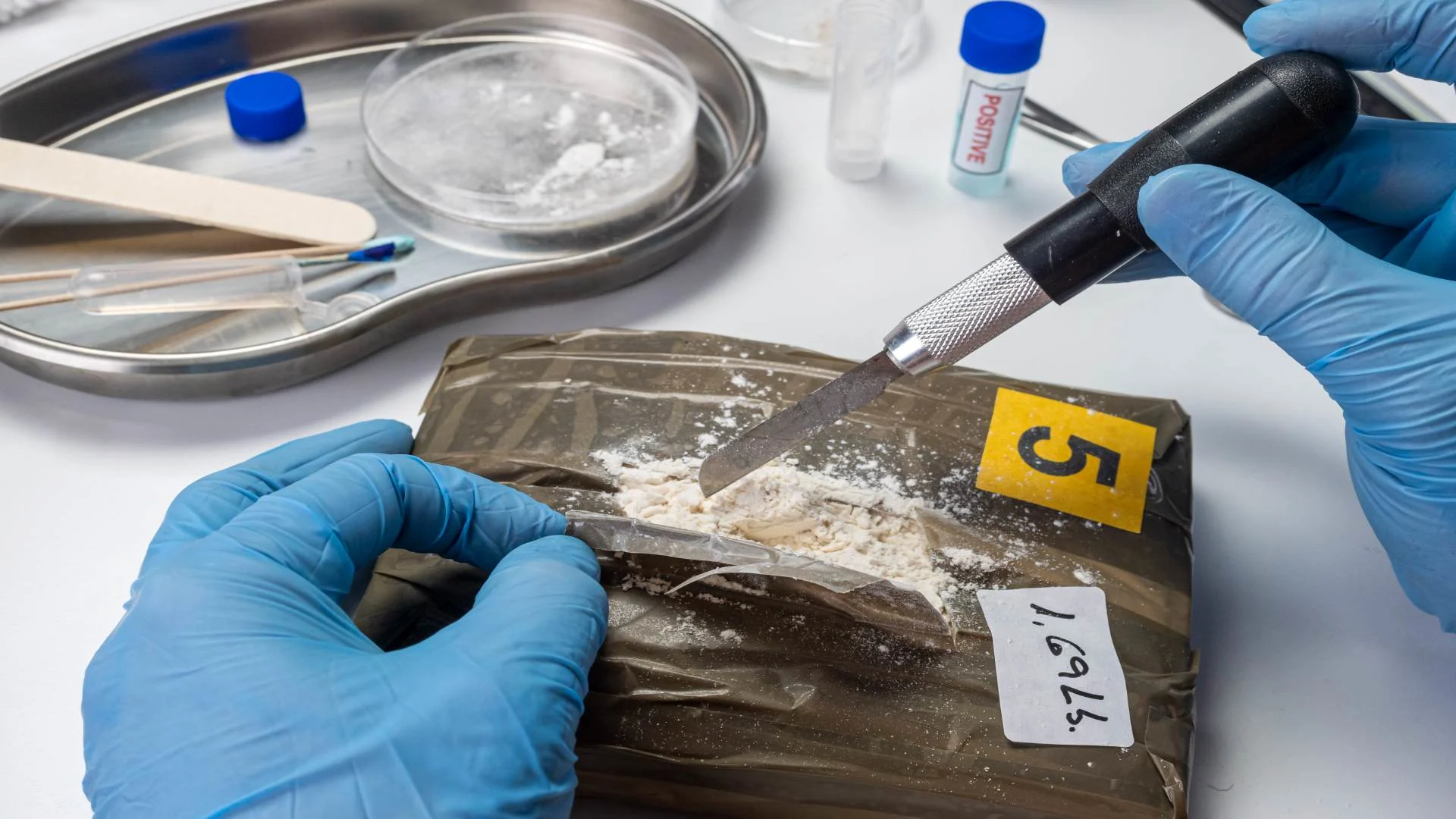 a bag of speed taken into police evidence being cut by a knife to test the substance inside.