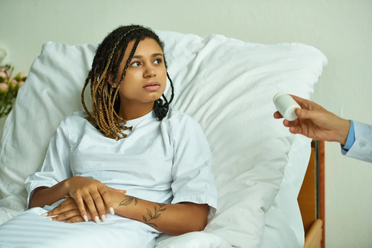 MAT: Woman dressed in hospital gown sitting in hospital bed