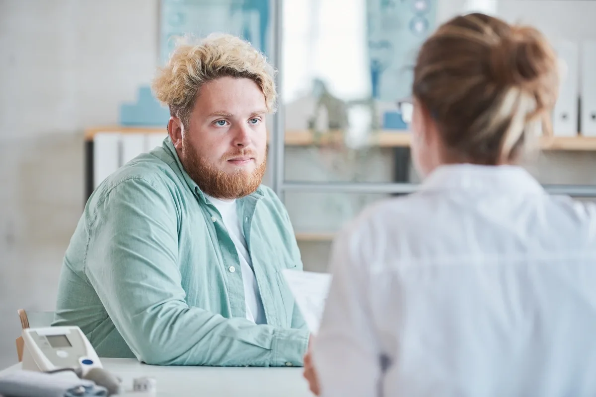 Inpatient Rehab: Man sitting with a primary care provider Inpatient Rehab: Man sitting with a primary care provider