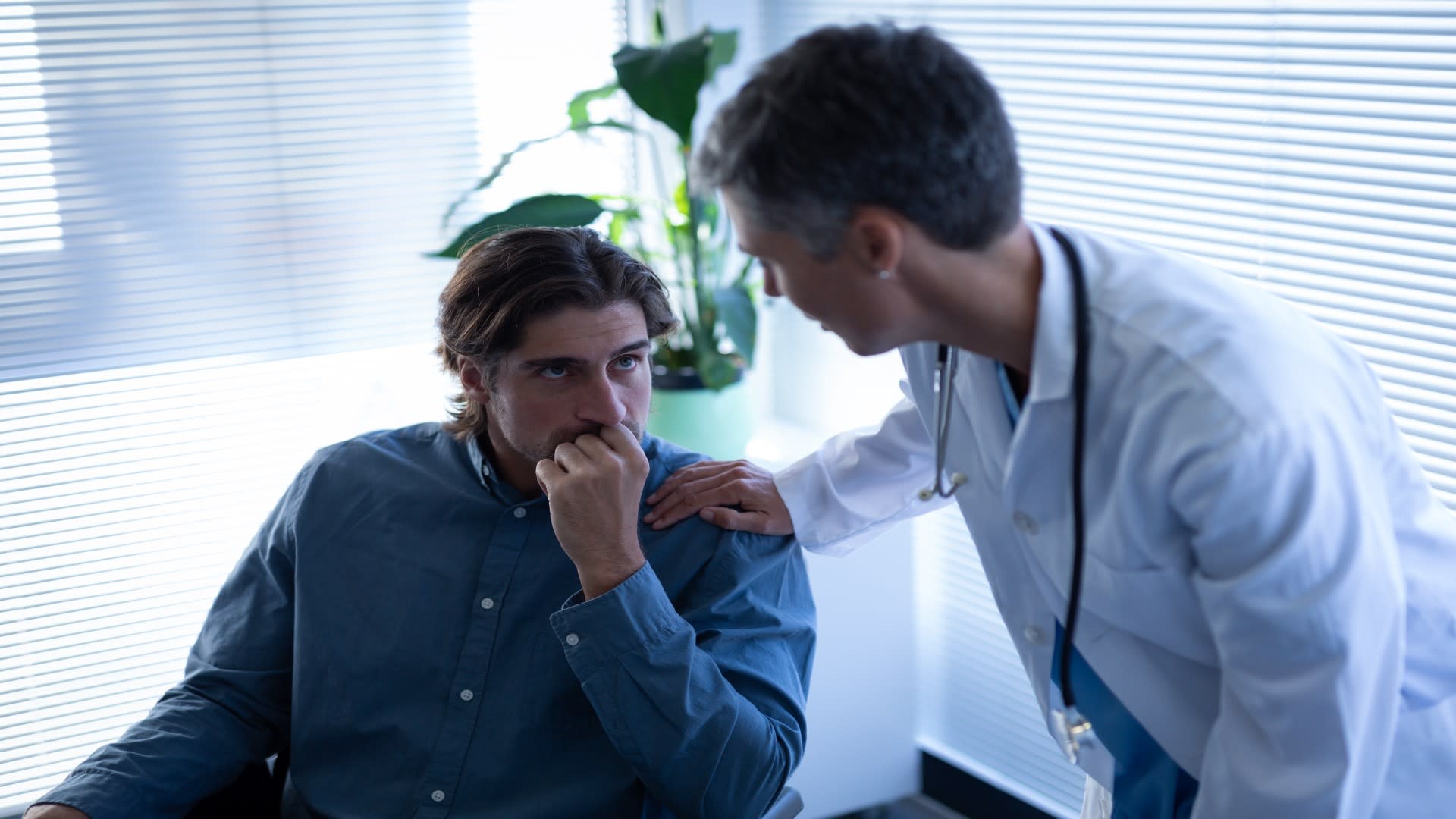Worried man speaking with a doctor about hydrocodone use and its potential side effects.