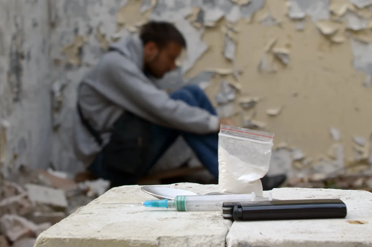 Cocaine Addiction: Man blurry in frame with needle and lighter Cocaine Addiction: Man blurry in frame with needle and lighter