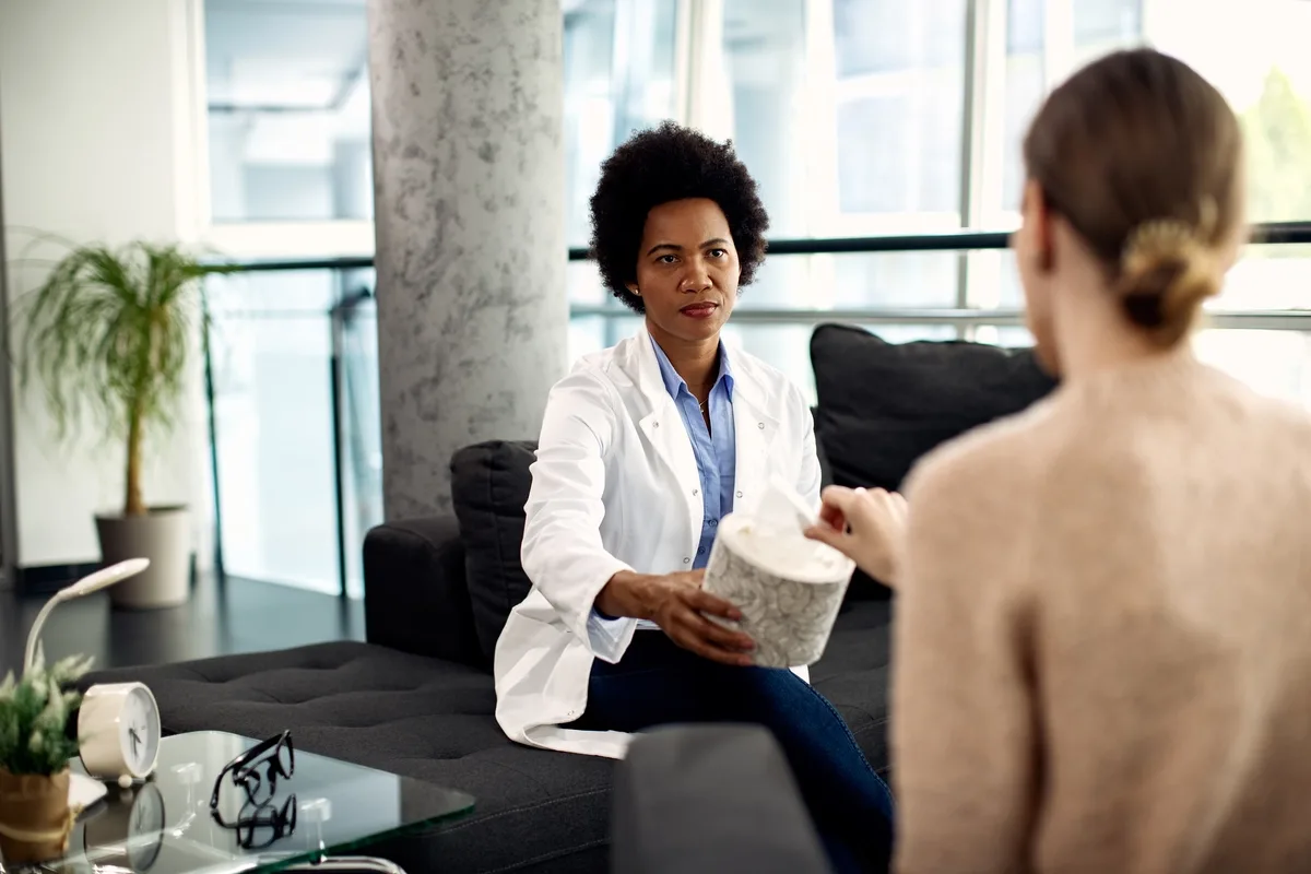 Motivational Interviewing: Doctor offering tissues to female patient