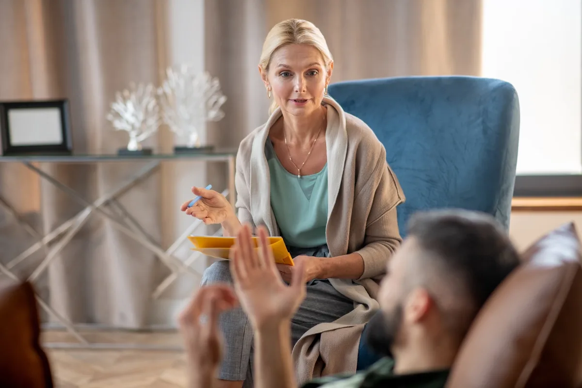 Individual Therapy: Therapist calmly talking to patient sitting in a chair