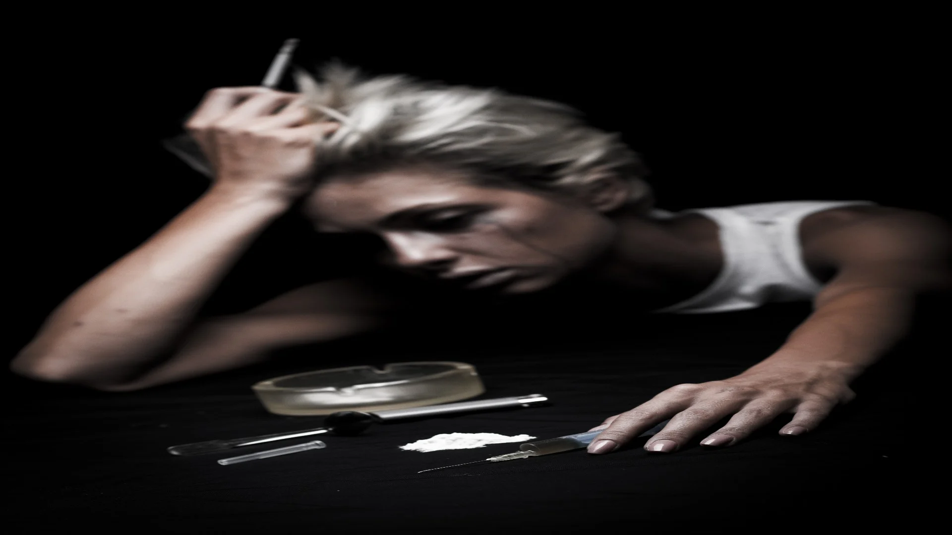 A woman appears exhausted and emotionally broken near drug paraphernalia, depicting the physical and psychological toll of meth withdrawal symptoms.