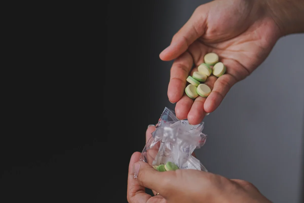 Synthetic Drug Addiction: Man taking pills from a baggie