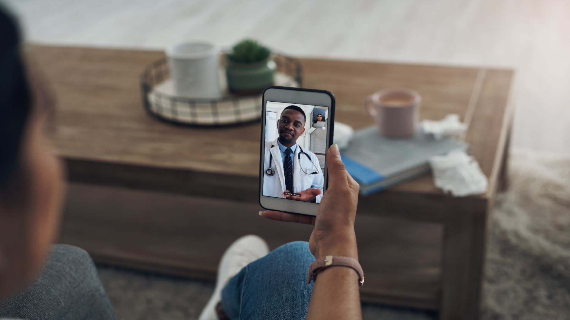 Close-up of a telehealth mental health services video call with a doctor, conducted on a smartphone in a cozy home setting.