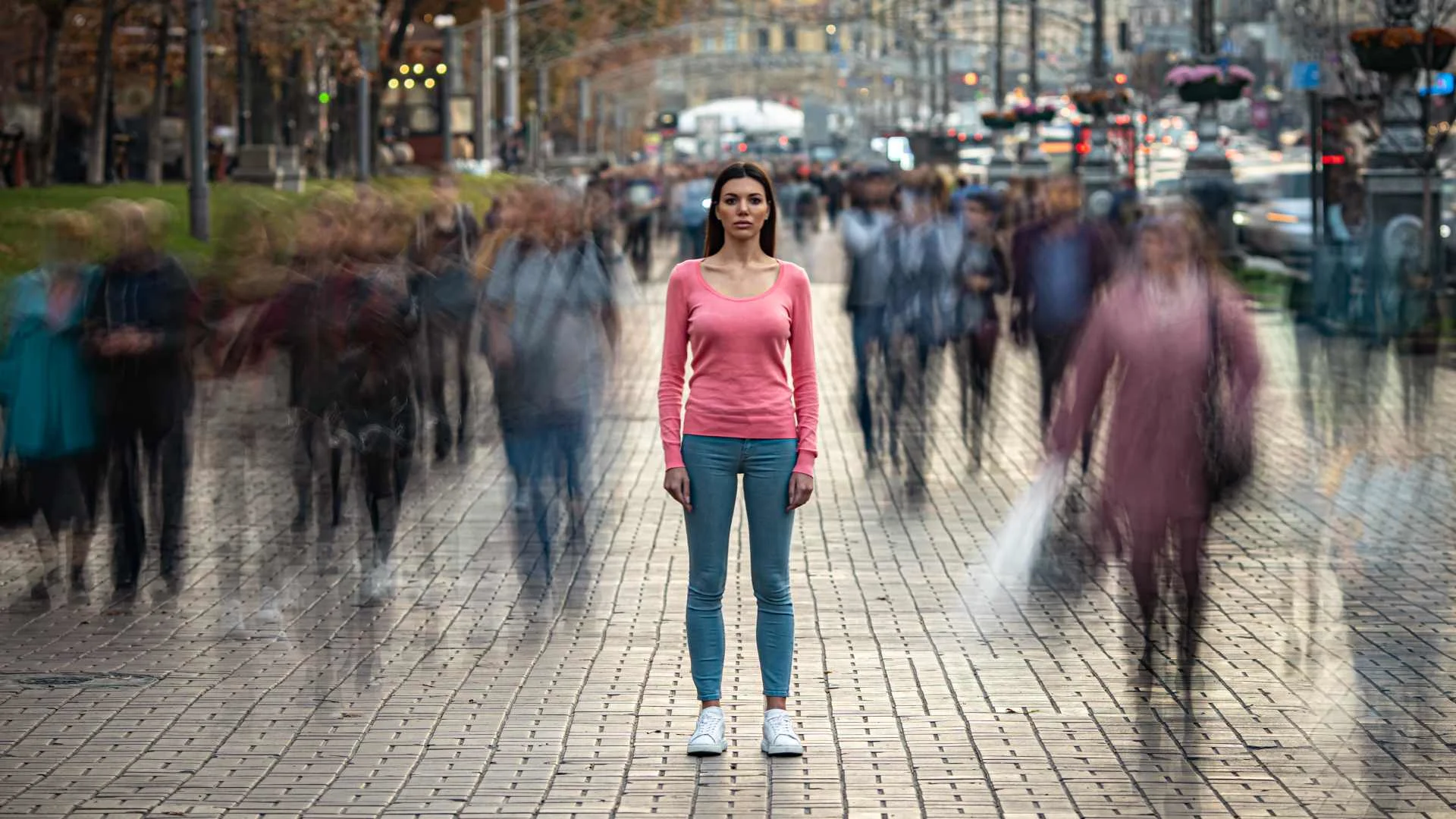 Woman standing still amid a fast-moving crowd, symbolizing the feeling of isolation and altered perception often asked about in ‘what is schizophrenia?’