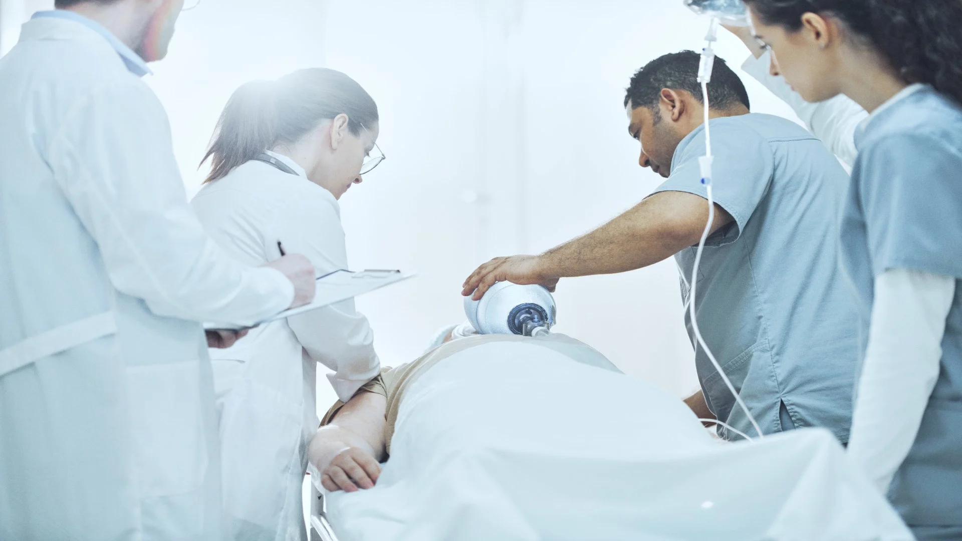 doctors gathered around a patient trying to save him with a breathing bag