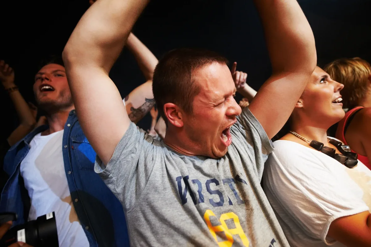 Cocaine Addiction: Man screaming with his hands up at a party