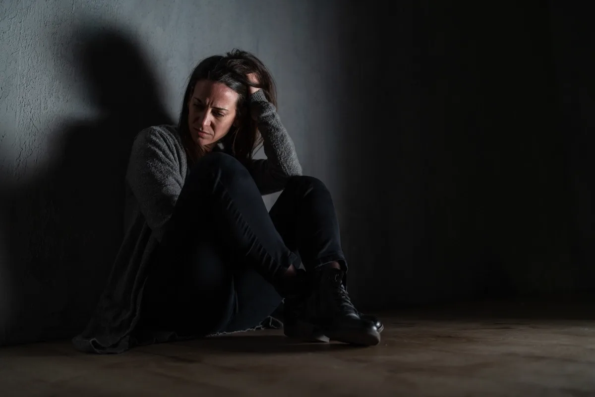 Inhalant Addiction: Woman sitting in the dark against a wall