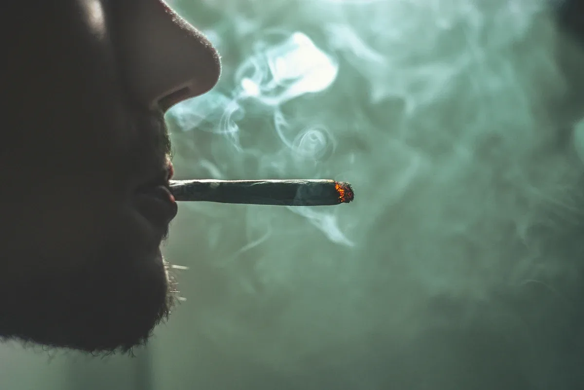Marijuana Addiction: Close up profile shot of a man smoking a joint Marijuana Addiction: Close up profile shot of a man smoking a joint
