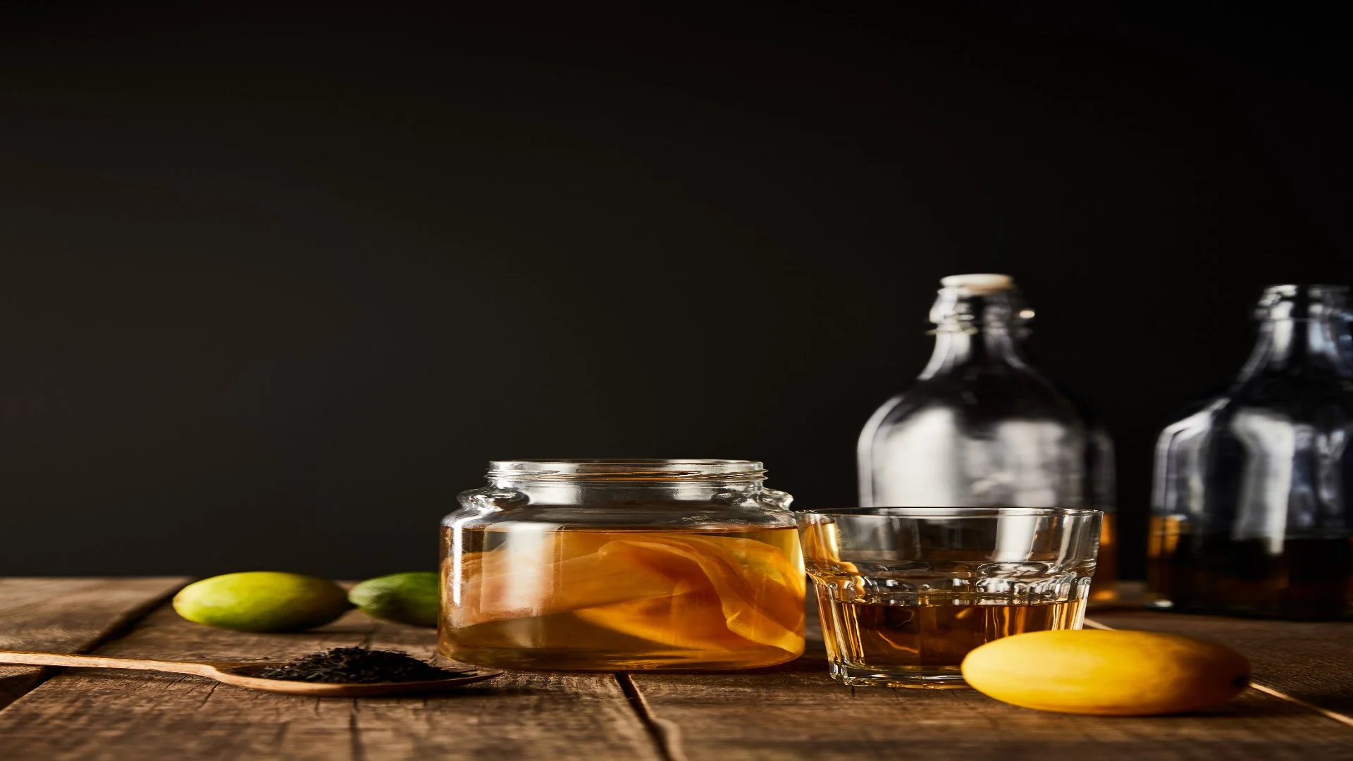 glass jar with kombucha near lime lemon spice and a whisky glass