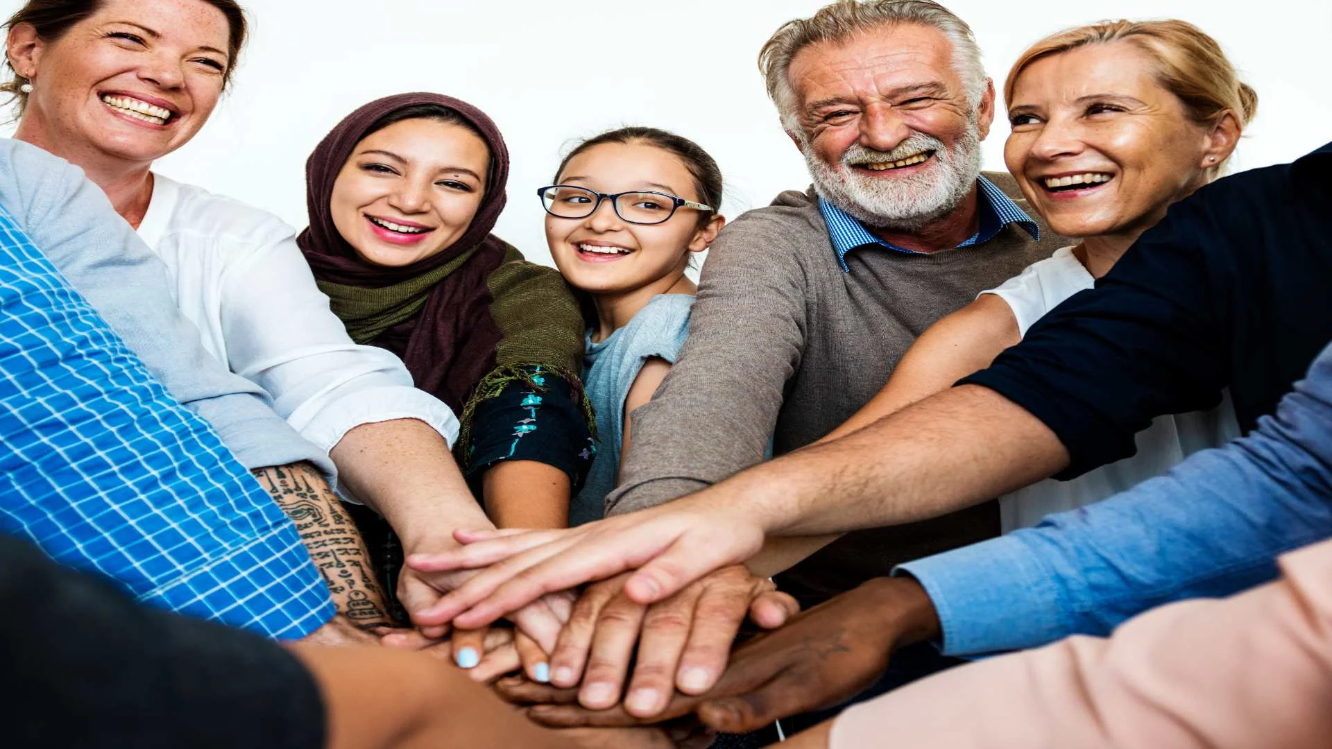 Supportive group of diverse people smiling with hands stacked, representing social connection and recovery in answering the question: what is schizophrenia?