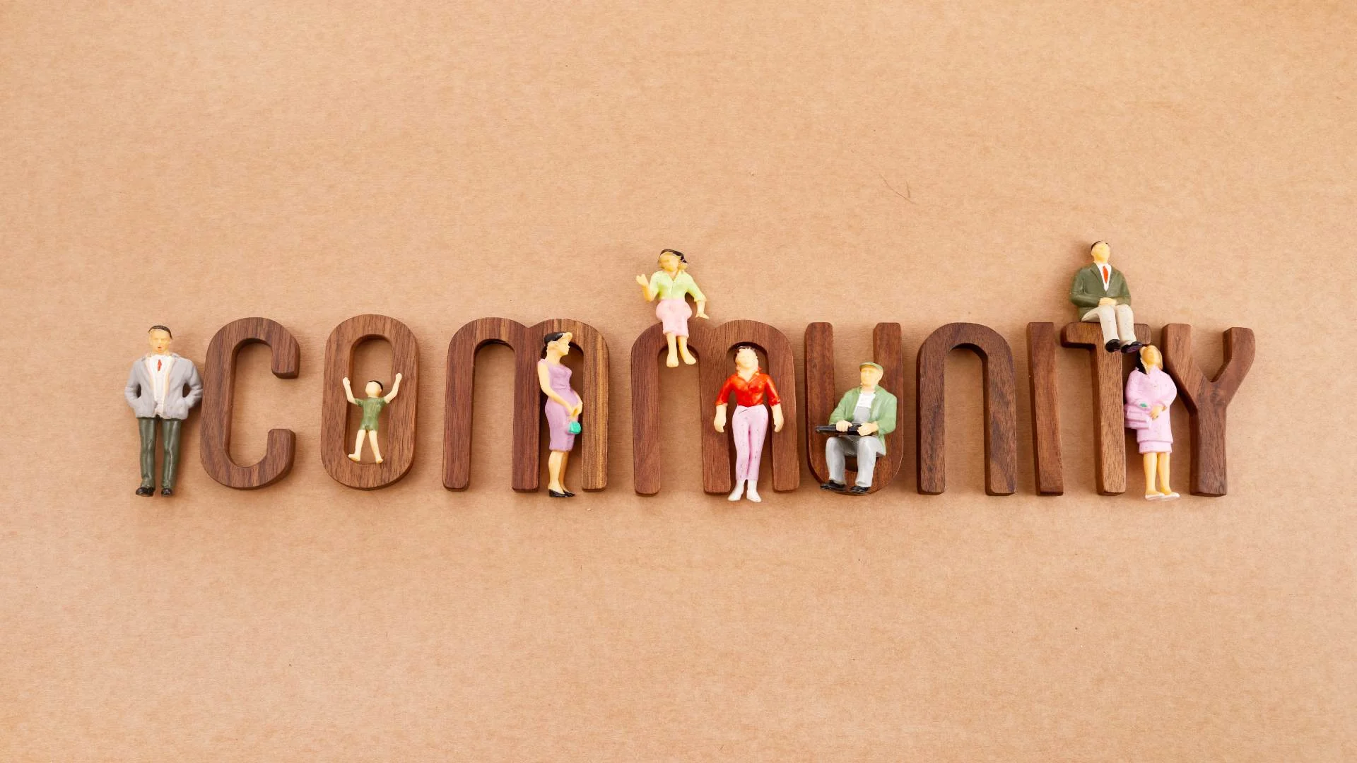 Miniature figurines representing diverse people standing on wooden letters spelling ‘community,’ symbolizing how OCD affects individuals across all walks of life.