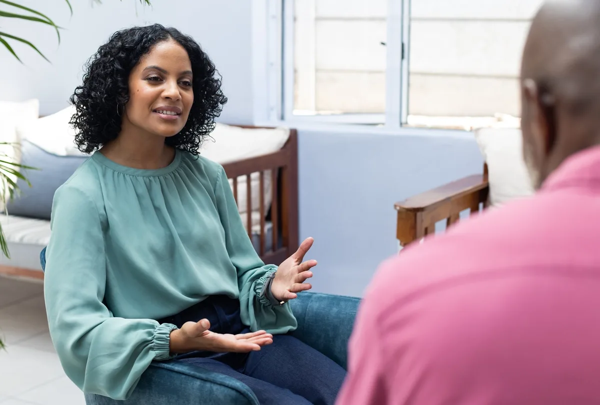 TMS: Woman talking to man in pink shirt