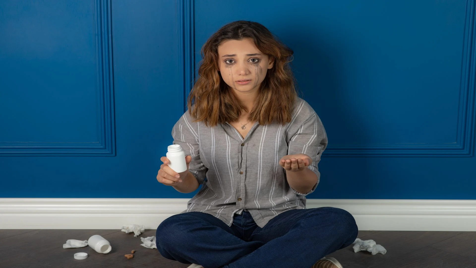 Benzodiazepines list depicted as a distressed woman holding a white pill bottle, highlighting the emotional toll and misuse risks of these medications.