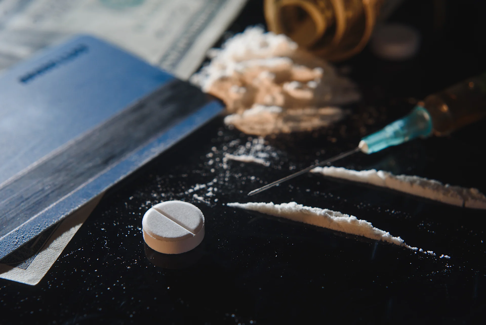a table with a pill and crushed pills as well as a syringe that represent schedule 1 drugs.