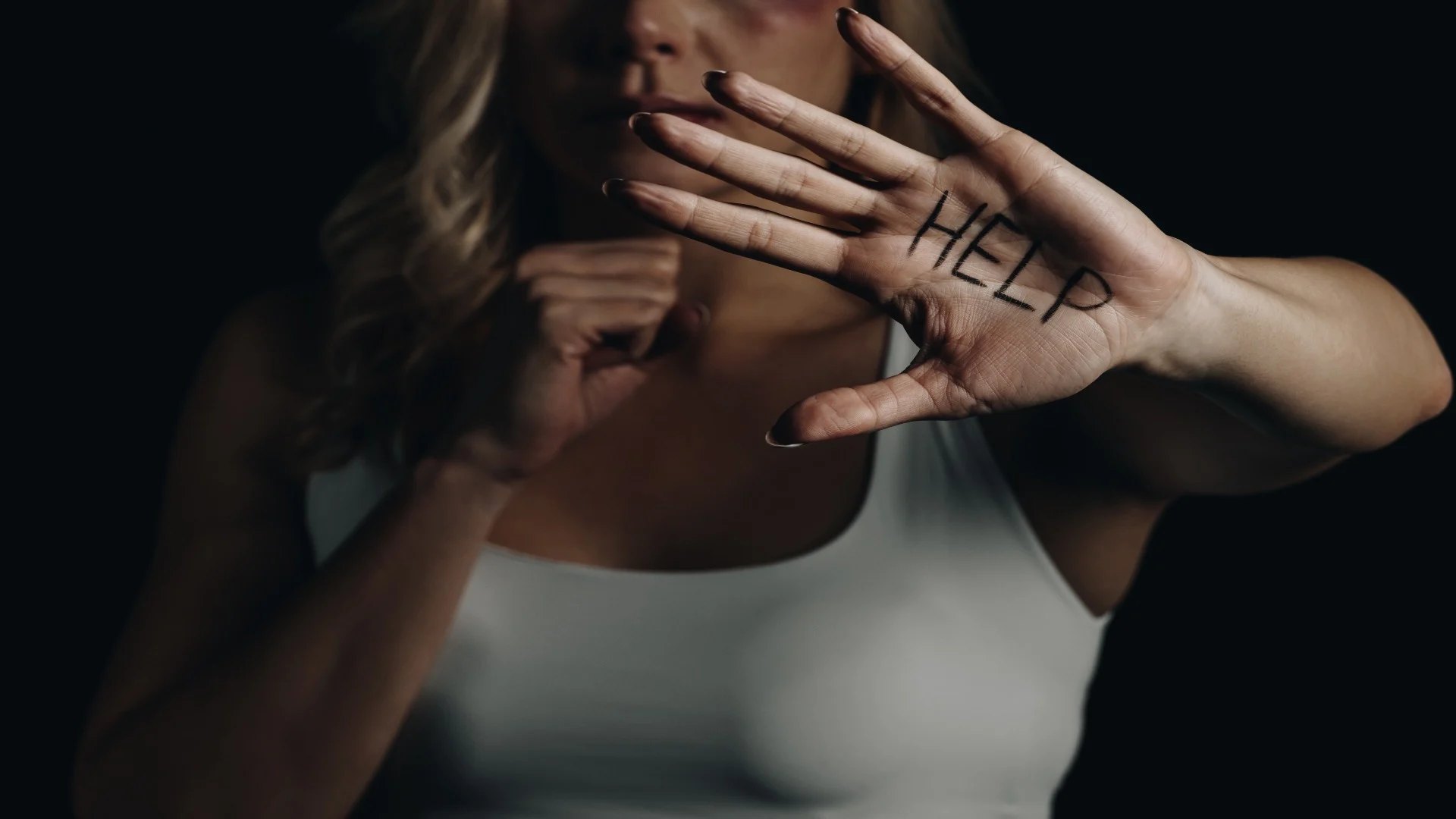 Distressed woman showing ‘HELP’ written on her palm, symbolizing the dissociation and fear experienced during a k hole episode.