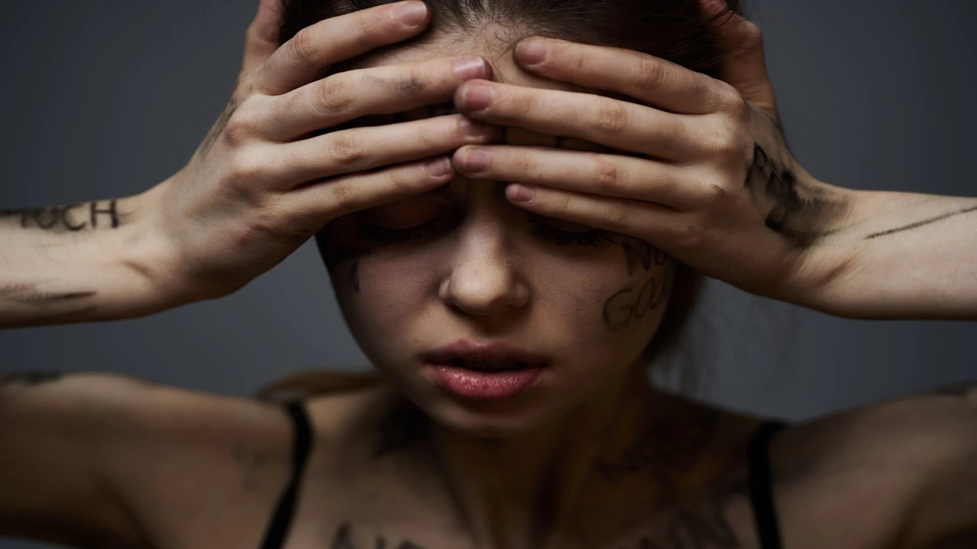 A distressed woman covers her face, her skin marked with harsh words, visually expressing the anxiety, shame, and depression often experienced as meth withdrawal symptoms.