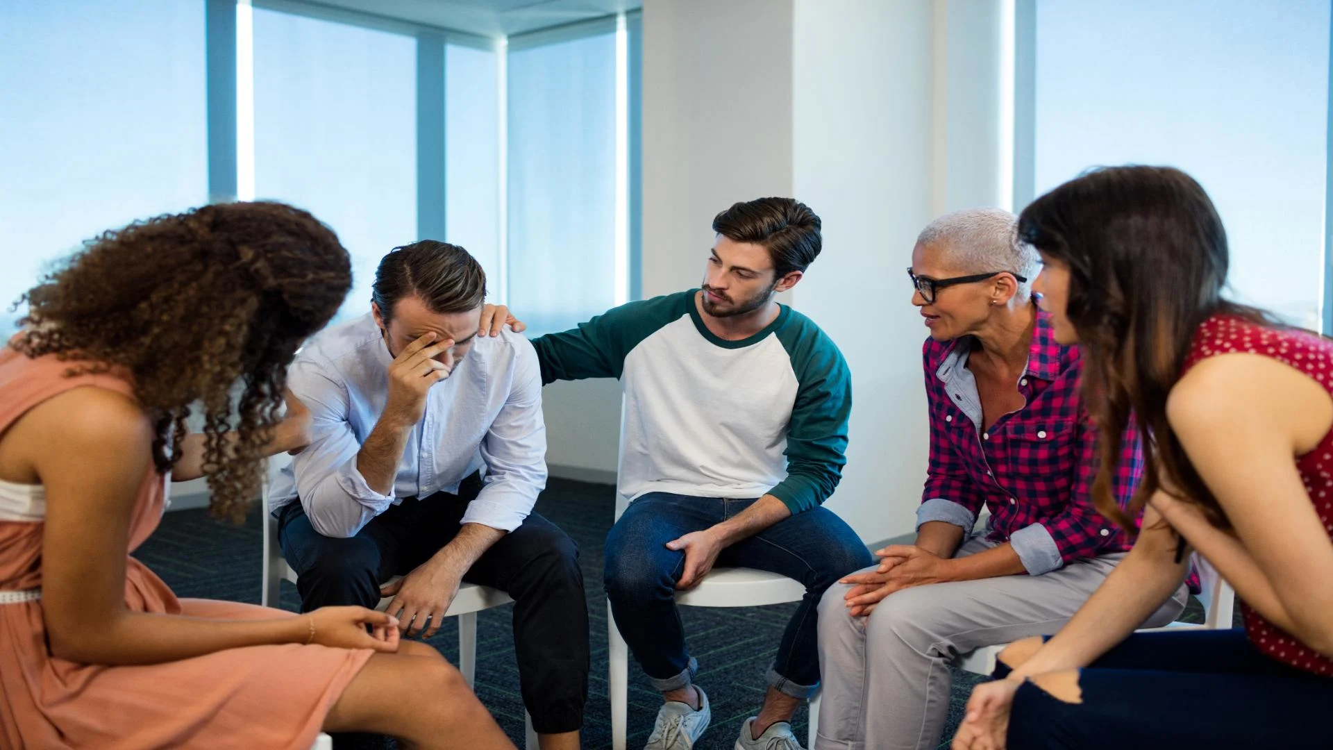 man in group sharing concerns about overcoming addiction and friends consoling him.
