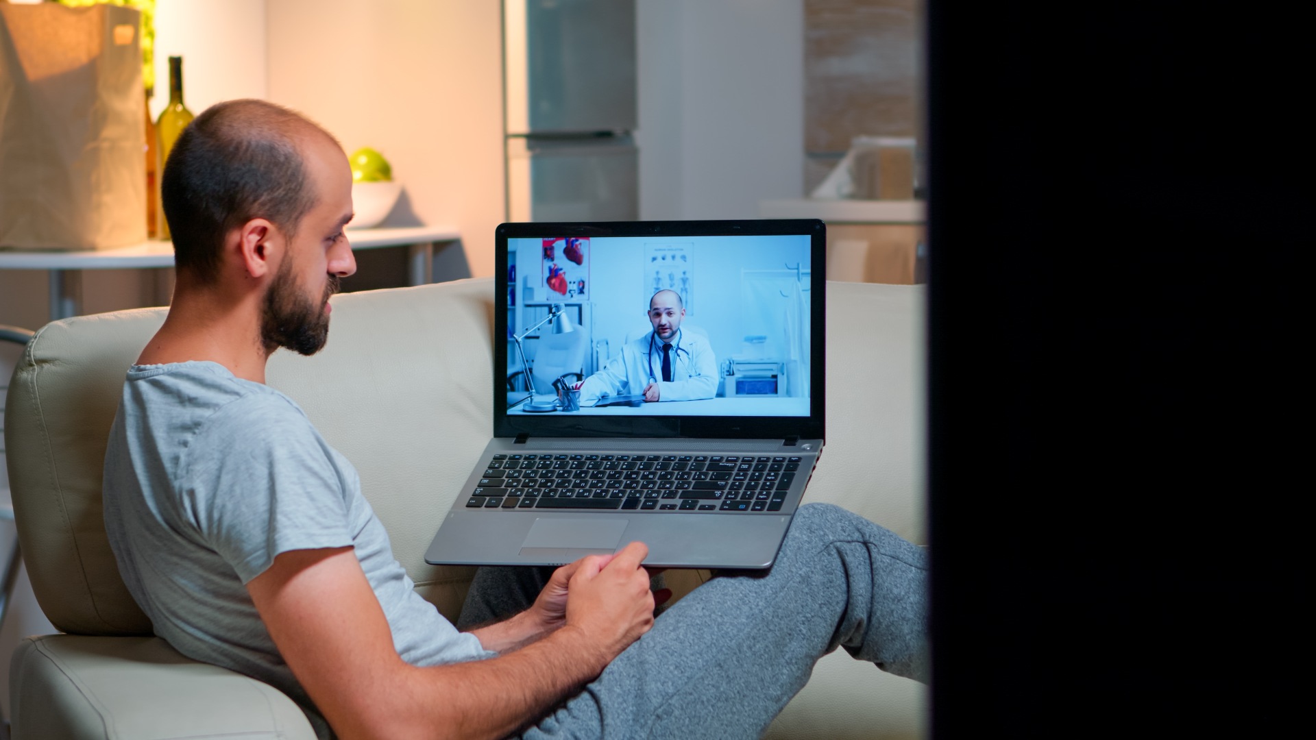Man engaging in an online addiction counseling video call from his couch, with a therapist speaking on-screen. Man engaging in an online addiction counseling video call from his couch, with a therapist speaking on-screen.