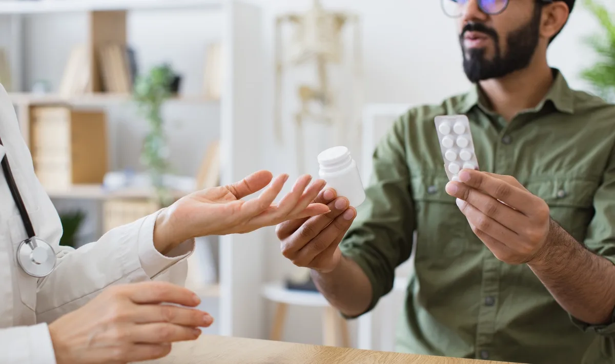 MAT: Man holding pills listening to a doctor