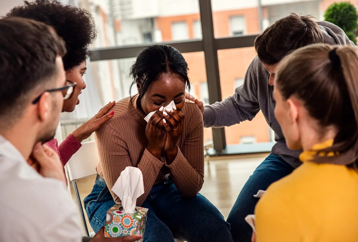 Woman being supported by her friends due to Catatonic Schizophrenia