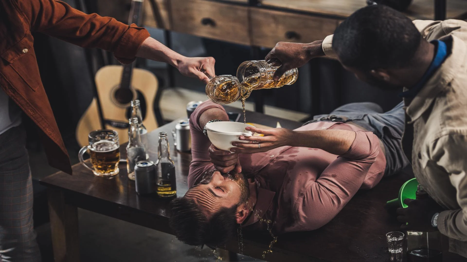 Alcohol intoxication symptoms illustrated in a risky drinking game where a man is funneled large quantities of beer by his friends, highlighting dangerous overconsumption.