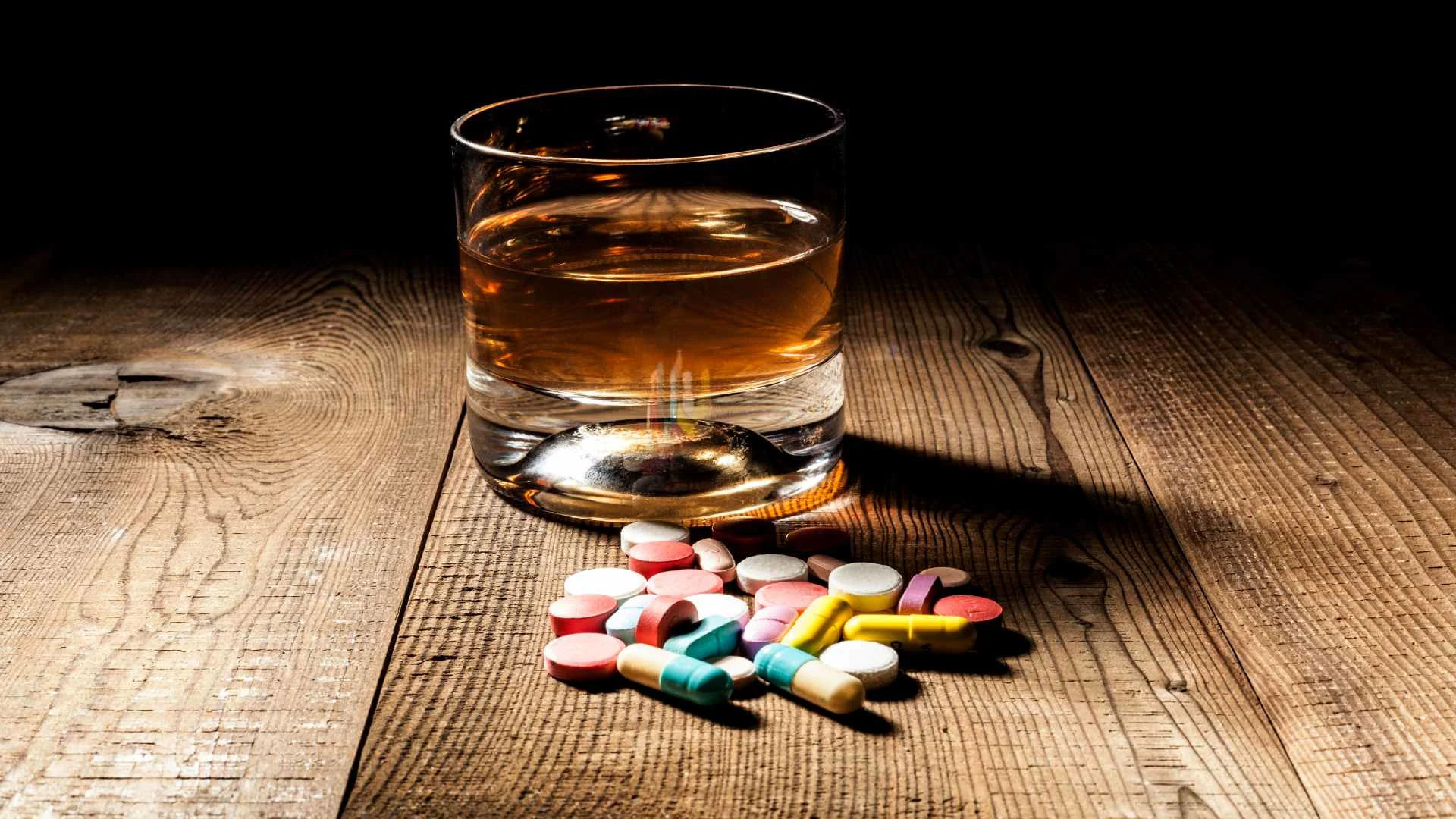 prednisone and alcohol together. A glass of whisky with pills on the table. prednisone and alcohol together. A glass of whisky with pills on the table.