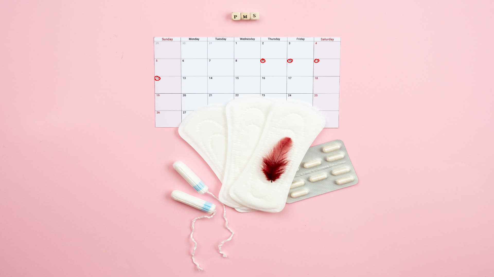 PMS calendar, sanitary pads, tampons, and feather stained with blood — representing menstrual symptoms and self-care essentials for PMDD management.
