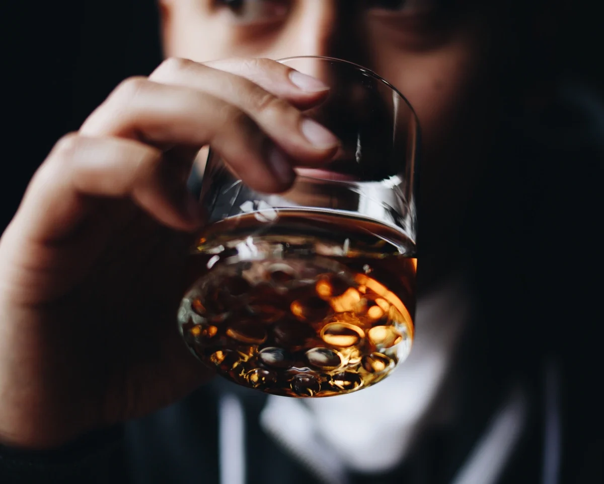 Alcohol Addiction: Man taking a drink of whiskey Alcohol Addiction: Man taking a drink of whiskey