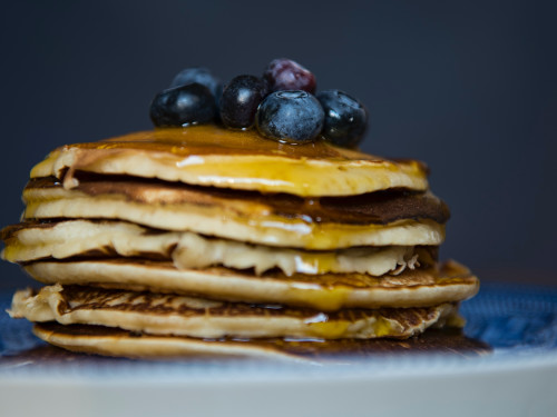 Stack of pancakes topped with syrup and blueberries