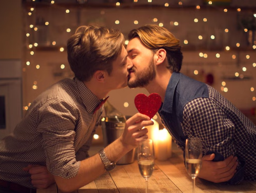 two men kissing one is holding a red love heart