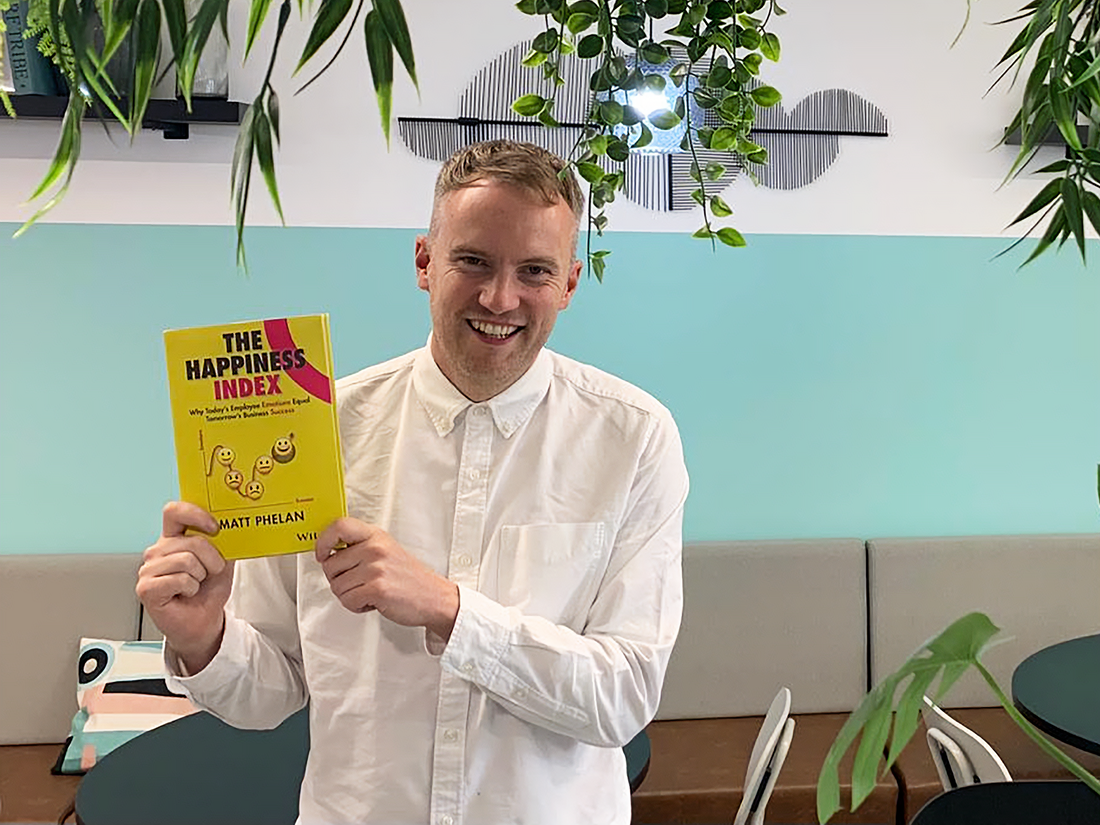 Matt Phelan holding his new book, The Happiness Index: Why today's employee emotions equal tomorrow's business success.