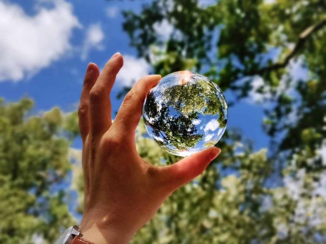 Developing an ESG strategy - Hand holding earth-like glass ball up to sky 