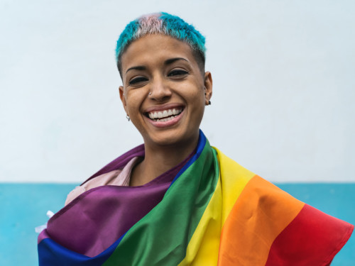 Woman wrapped in rainbow flag representative of LGBTQ+ community