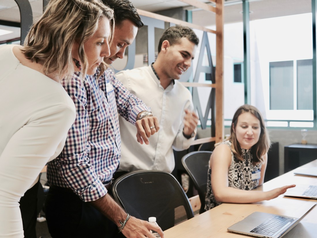 Benefits of employee engagement surveys - People huddled around laptops at work