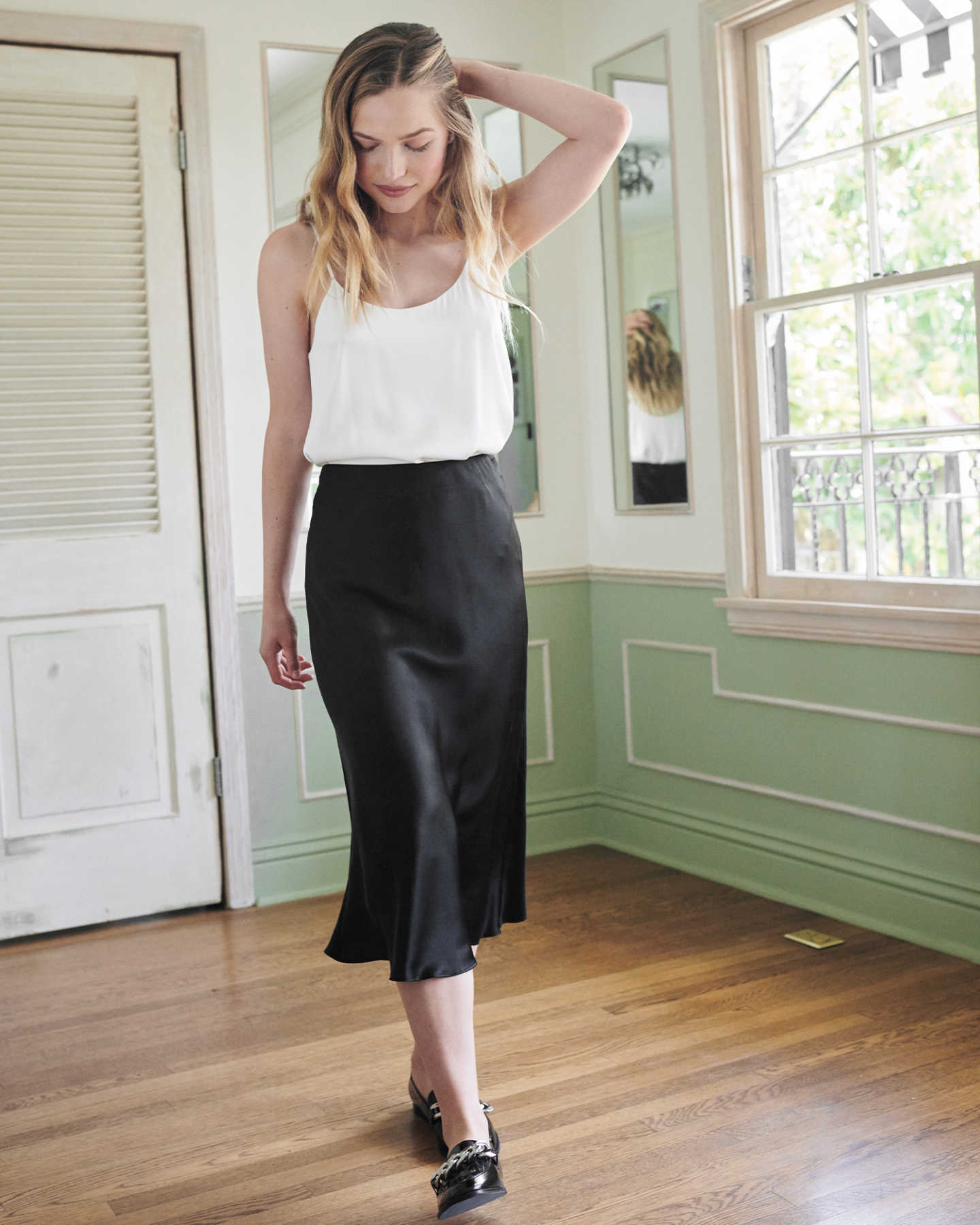 Woman wearing black silk skirt and white silk camisole