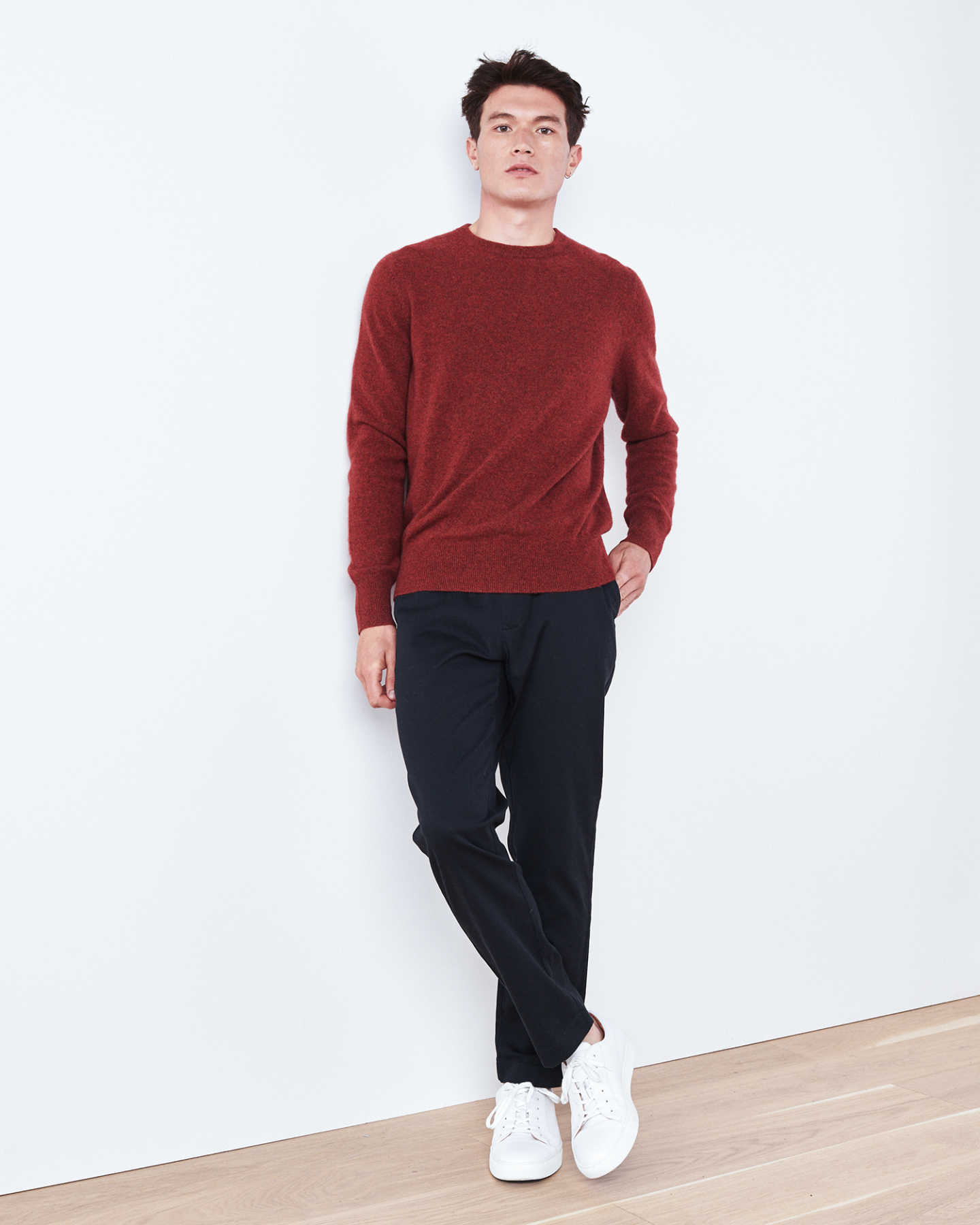 Man wearing red men's cashmere sweater against wall