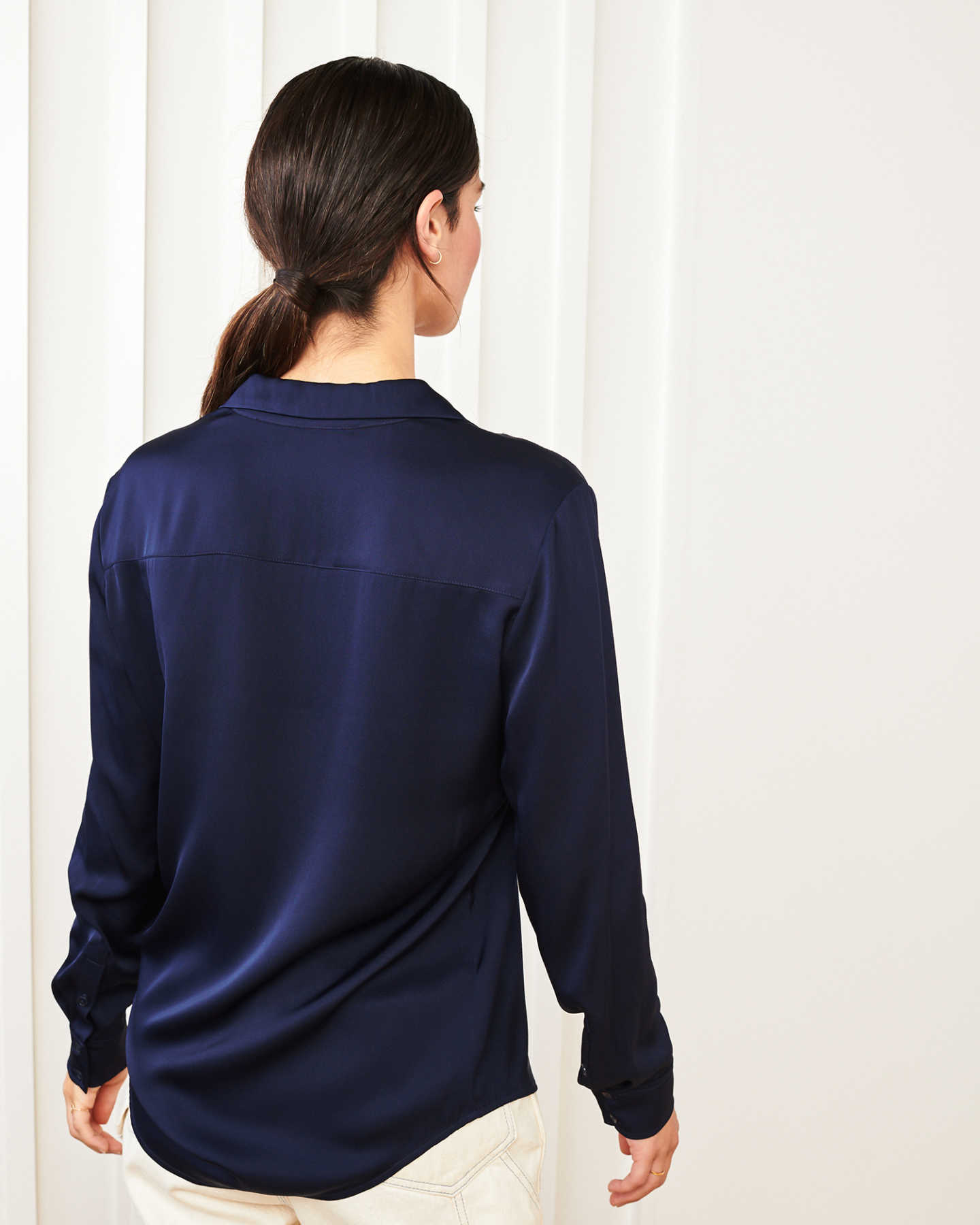 woman wearing silk notch collar blouse in navy from back