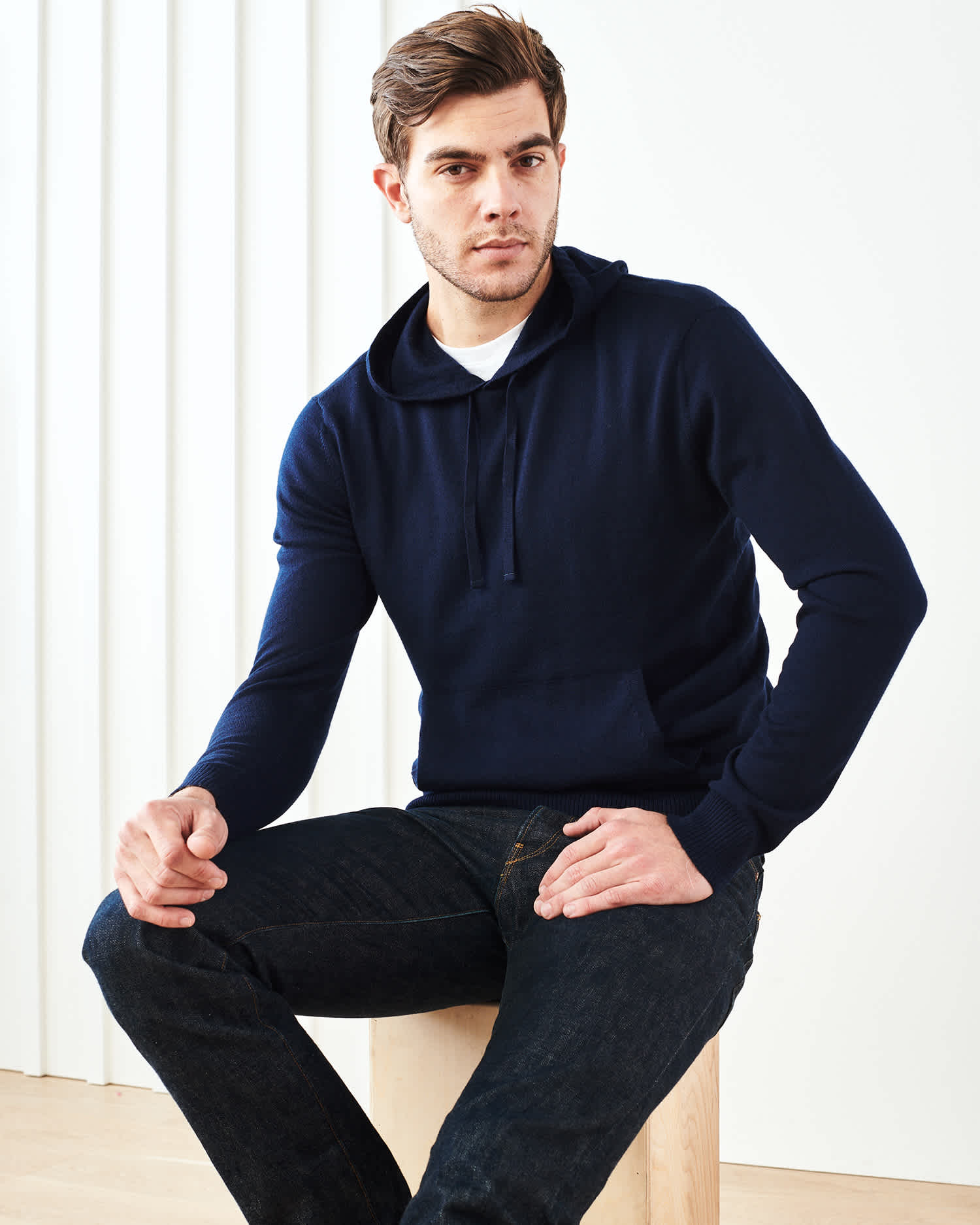 Man wearing merino wool hoodie in navy sitting