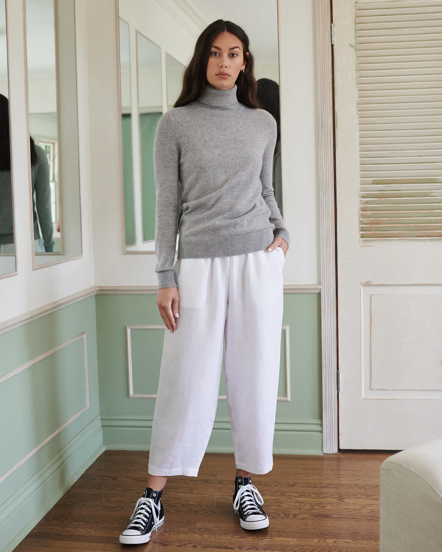 Woman wearing grey cashmere turtleneck sweater standing