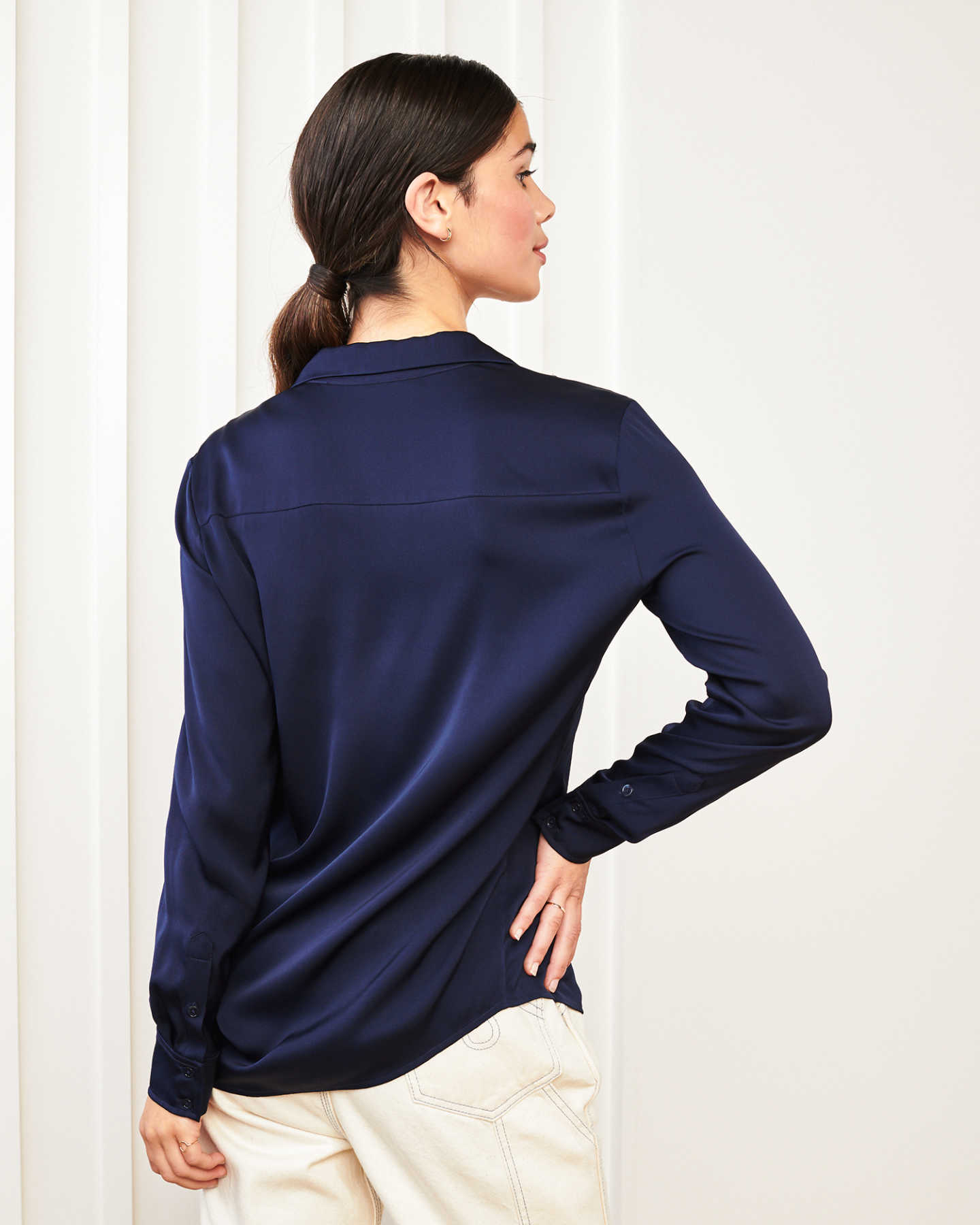 woman wearing silk notch collar blouse in navy with hand on hip