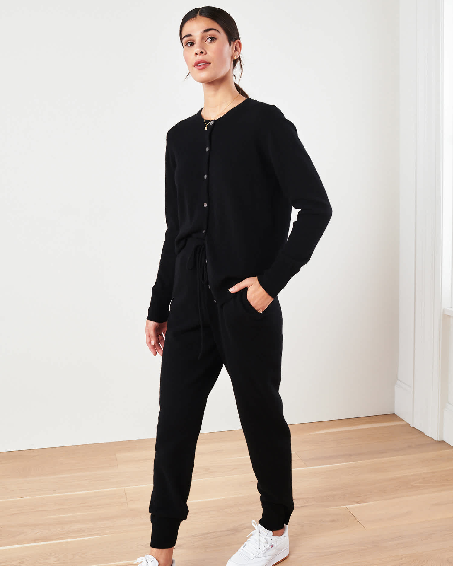 Woman wearing black cashmere cardigan sweater and black cashmere sweatpants walking