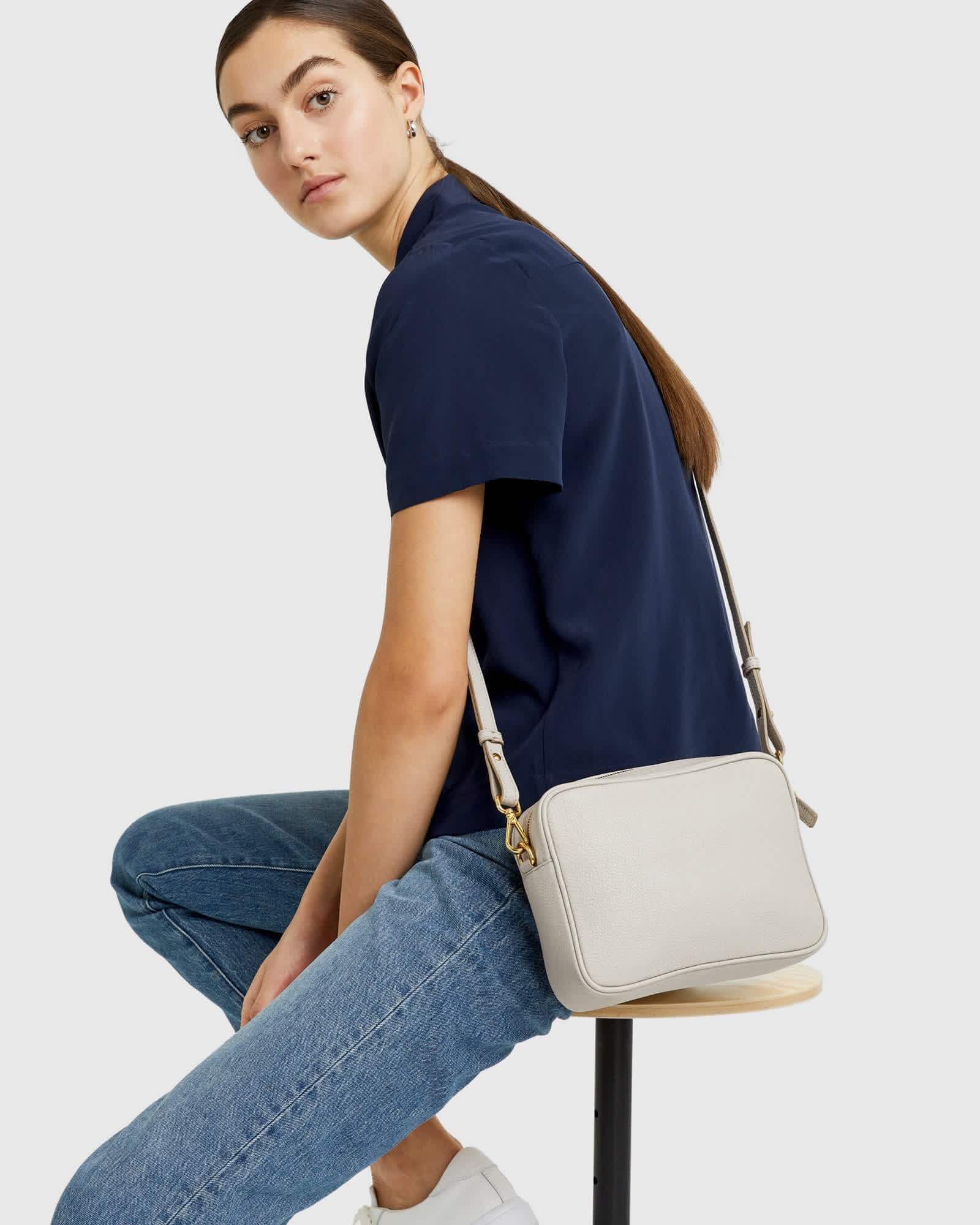 woman wearing Italian leather crossbody bag in stone and navy blouse